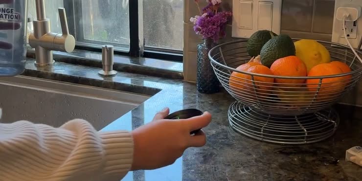A hand holding a Sponge tracker on a kitchen counter beside a Sponge-branded water bottle